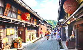 A street with buildings and people walking
Description automatically generated