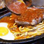 A spoon pouring sauce onto a plate of food Description automatically generated