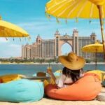 A person sitting on a beach with yellow umbrellas Description automatically generated