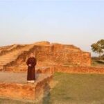 A person standing in front of a stone structure Description automatically generated