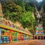A colorful building with a slide with Batu Caves in the background AI-generated content may be incorrect.