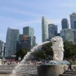 A statue of a lion with a city in the background Description automatically generated