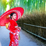 A person in a red dress with a red umbrella Description automatically generated