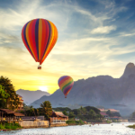 Hot air balloons flying over a river Description automatically generated