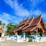 Wat Xieng Thong with a pool in front of it Description automatically generated