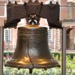 A large bell with a broken piece of wood Description automatically generated