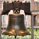 A large bell with a broken piece of wood Description automatically generated