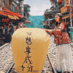 A person standing on train tracks with a large yellow lantern Description automatically generated