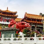 A red dragon statue in front of a building Description automatically generated