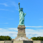 A statue of liberty with people standing around Description automatically generated